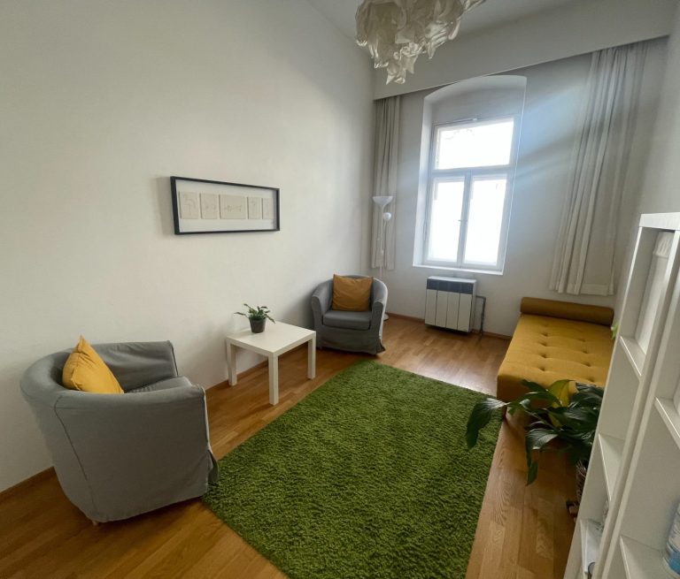 Gemütlicher Raum mit zwei Sessel, einem Sofa und einem Teppich in Grün.